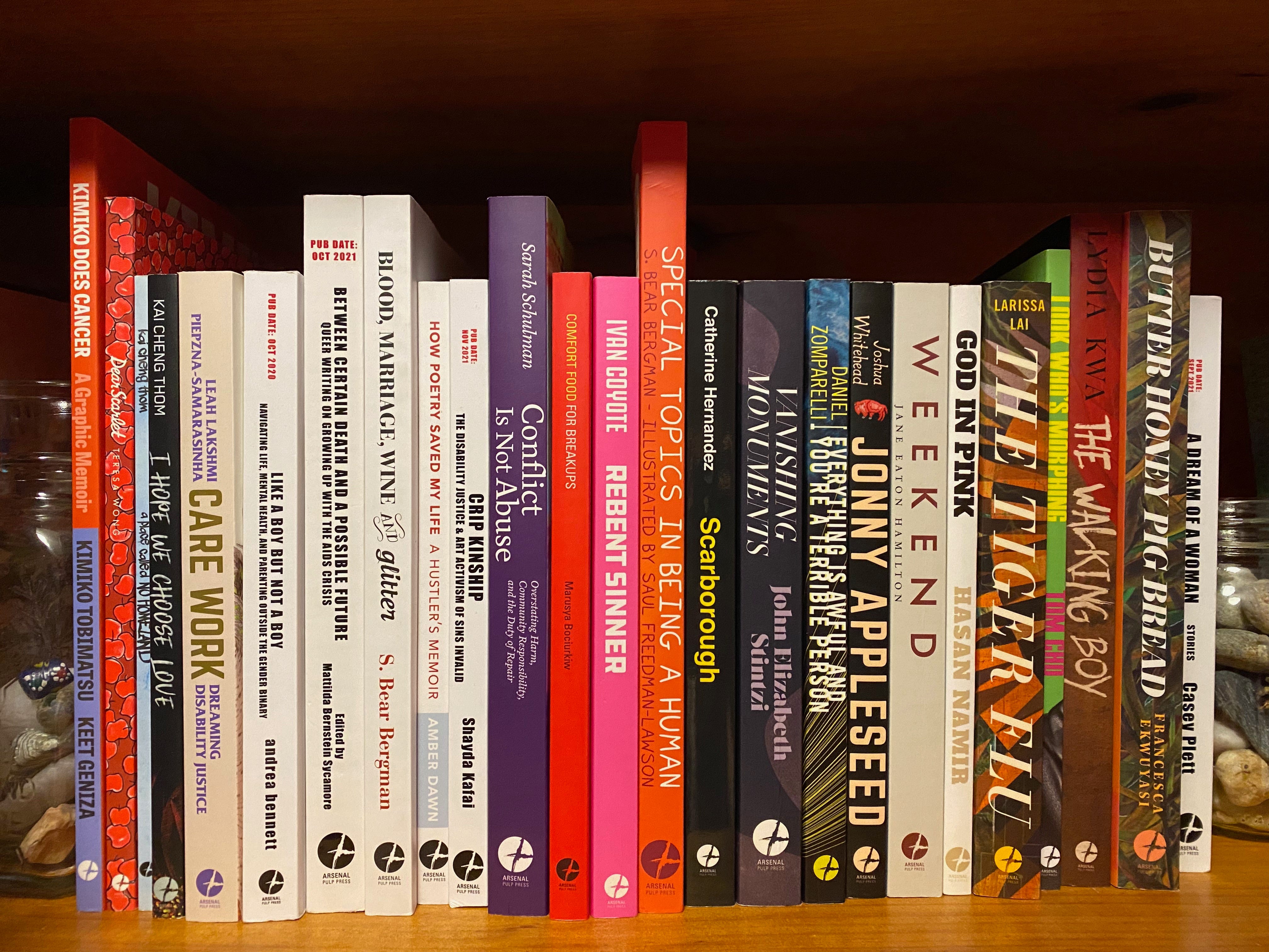 A shelf of paperback books of various sizes and colors, all published by Arsenal Pulp.