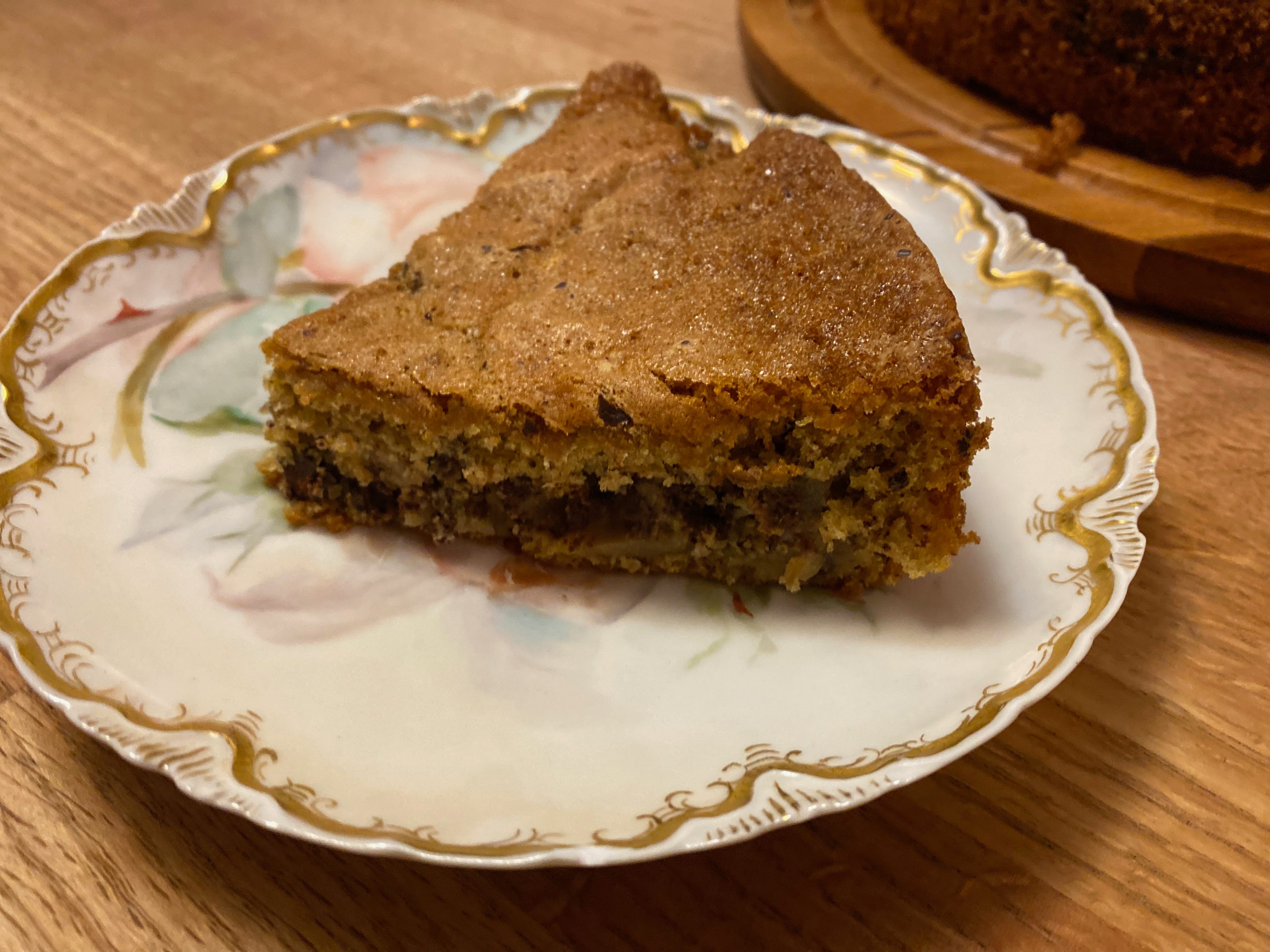 A golden brown slice of chocolate pear cake on a painted ceramic plate.