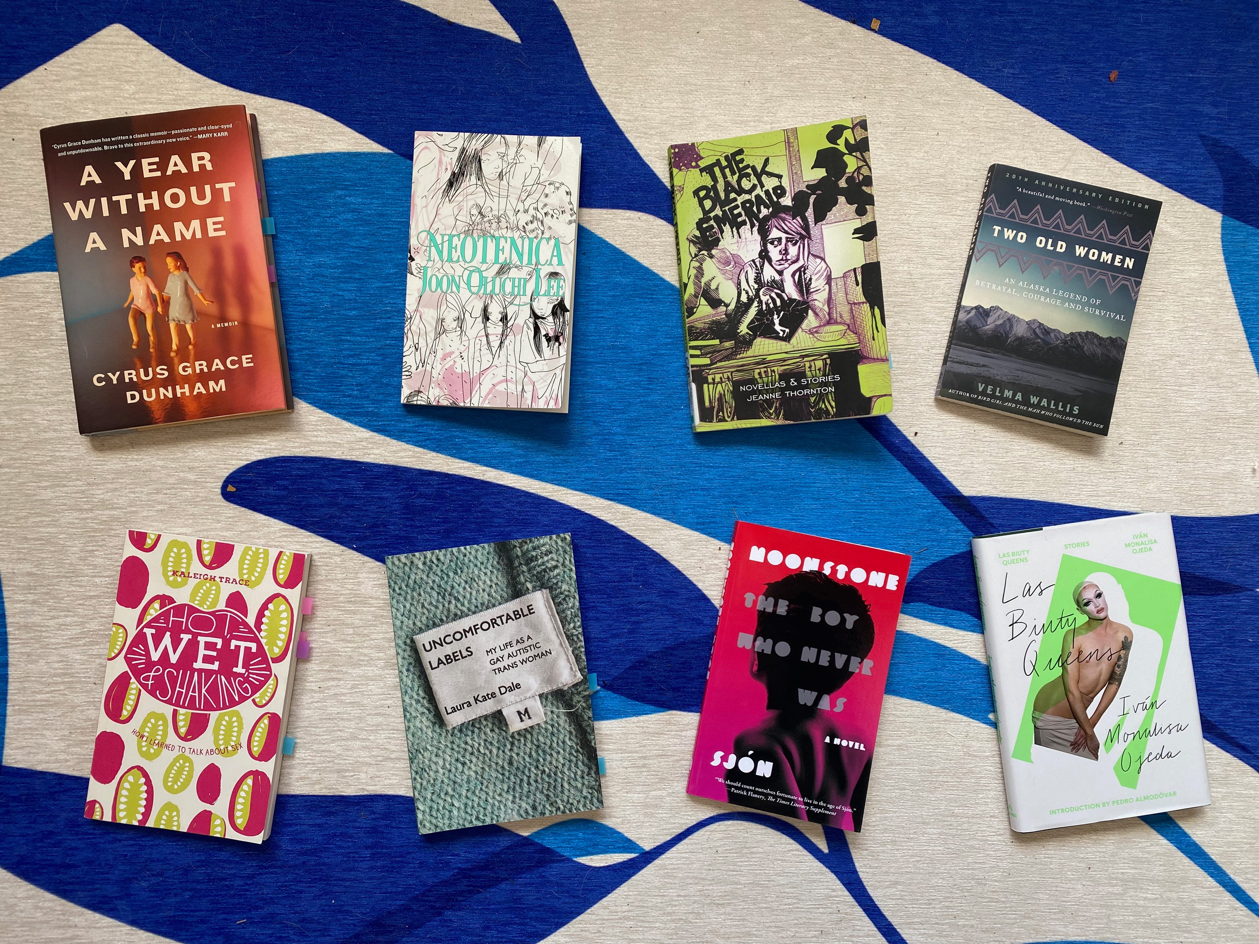 The books mentioned below, laid out face-up in two rows of four, on a blue and white pattered rug.