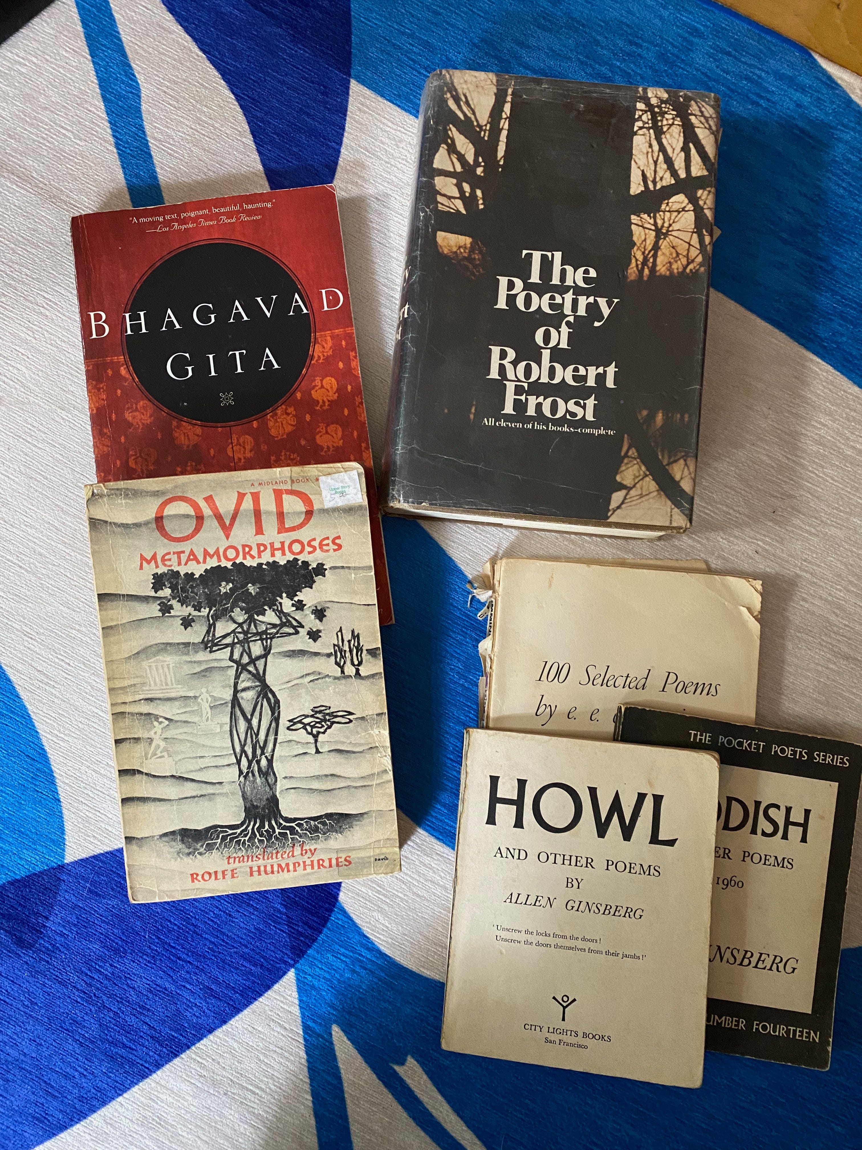 A selection of old and well-loved books piled on a blue rug.