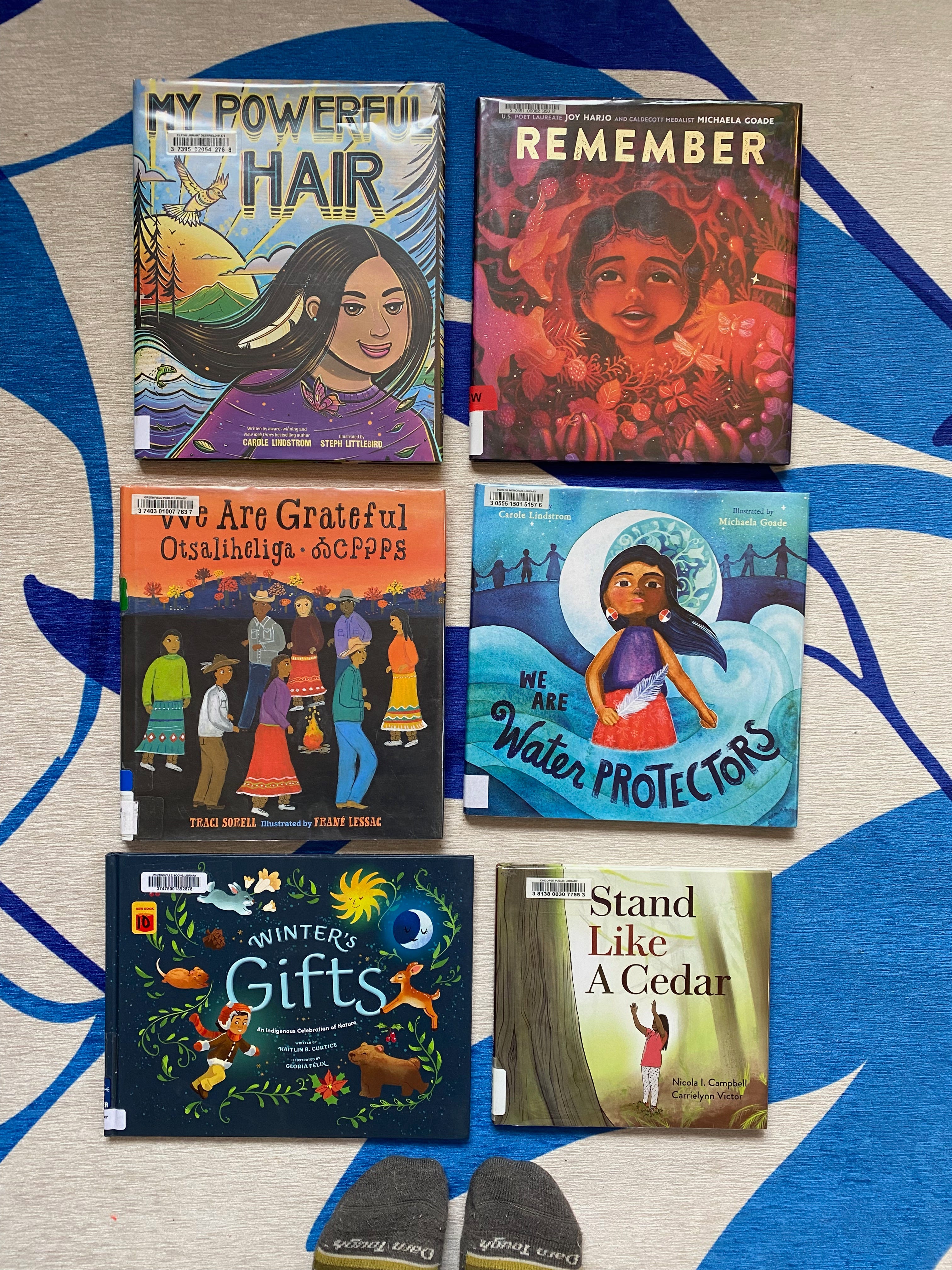 The six listed books laid out on a blue and white rug.