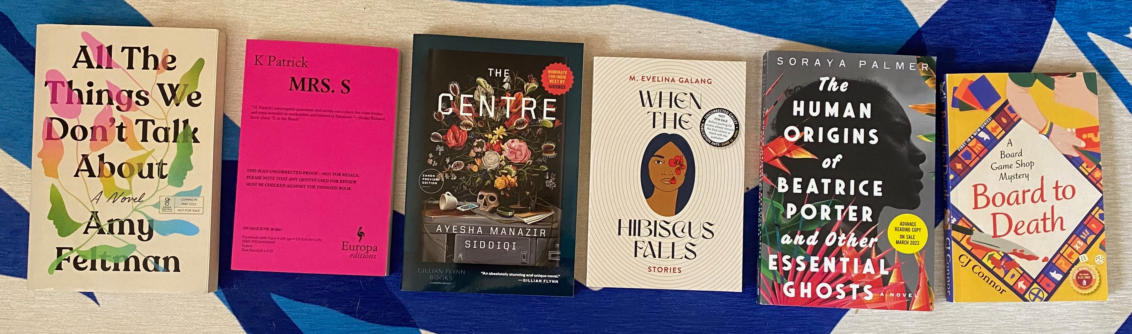 The listed books laid out in a row on a blue and white rug.