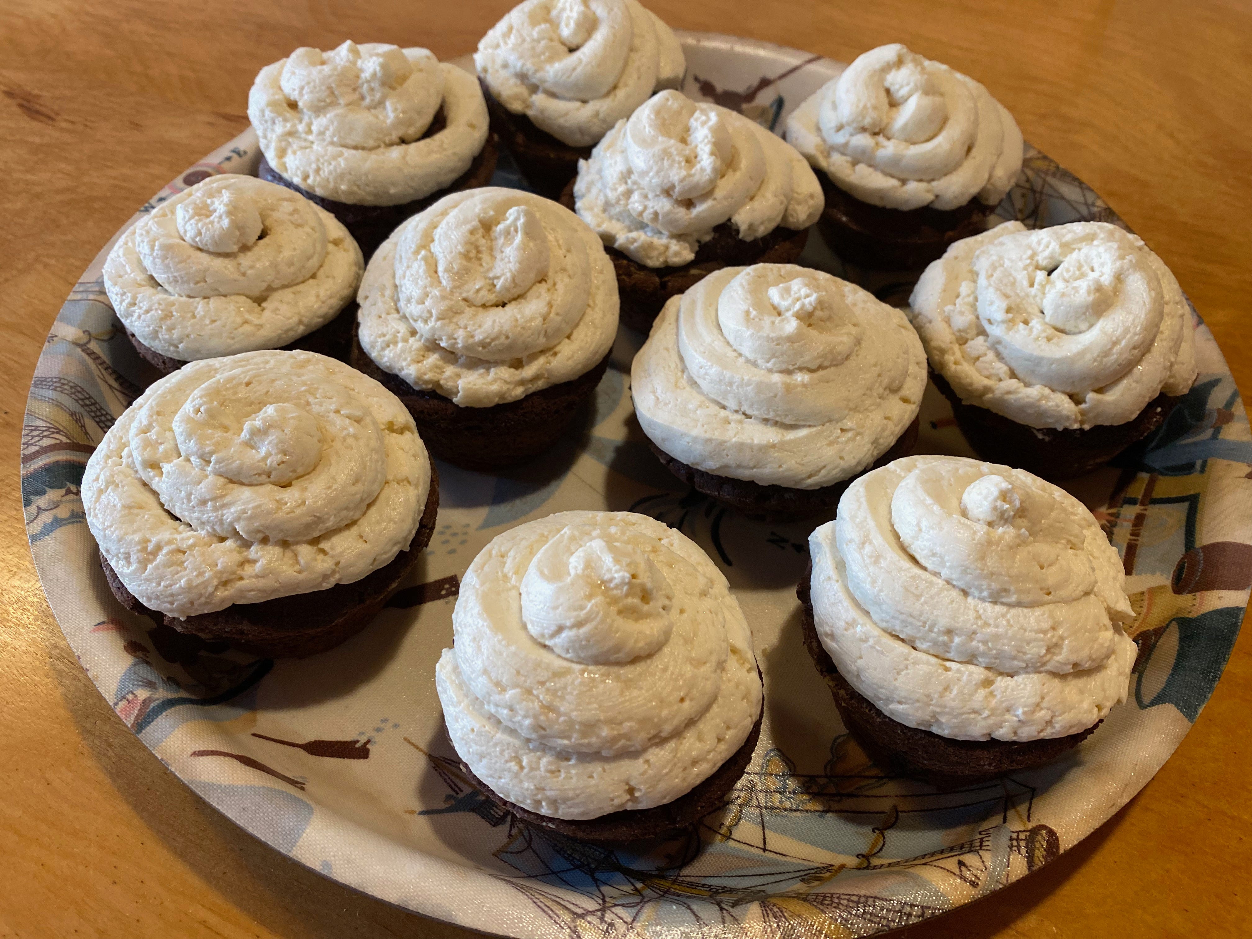A tray of chocolate cupcakes topped with swirls of vanilla frosting.