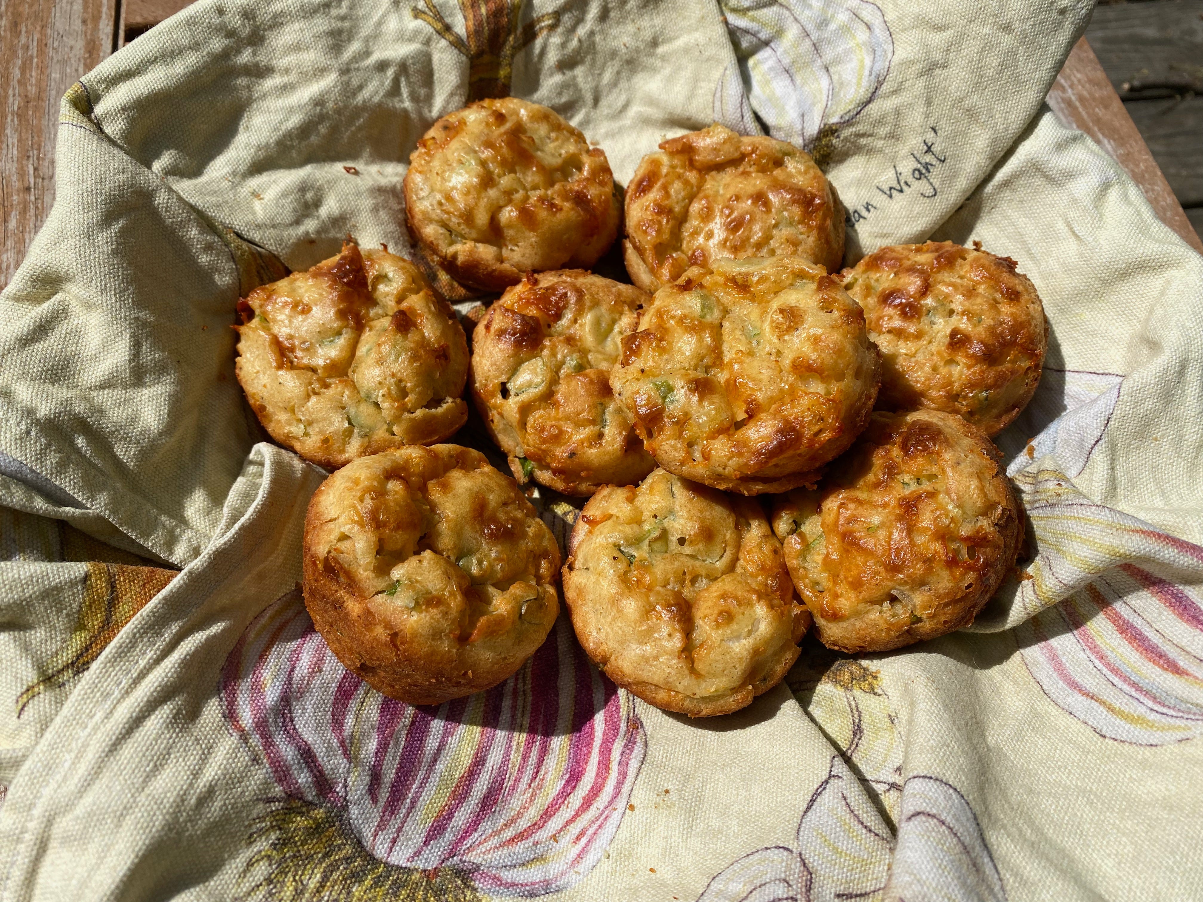 A cloth-lined basked filled with golden brown cheese puffers.